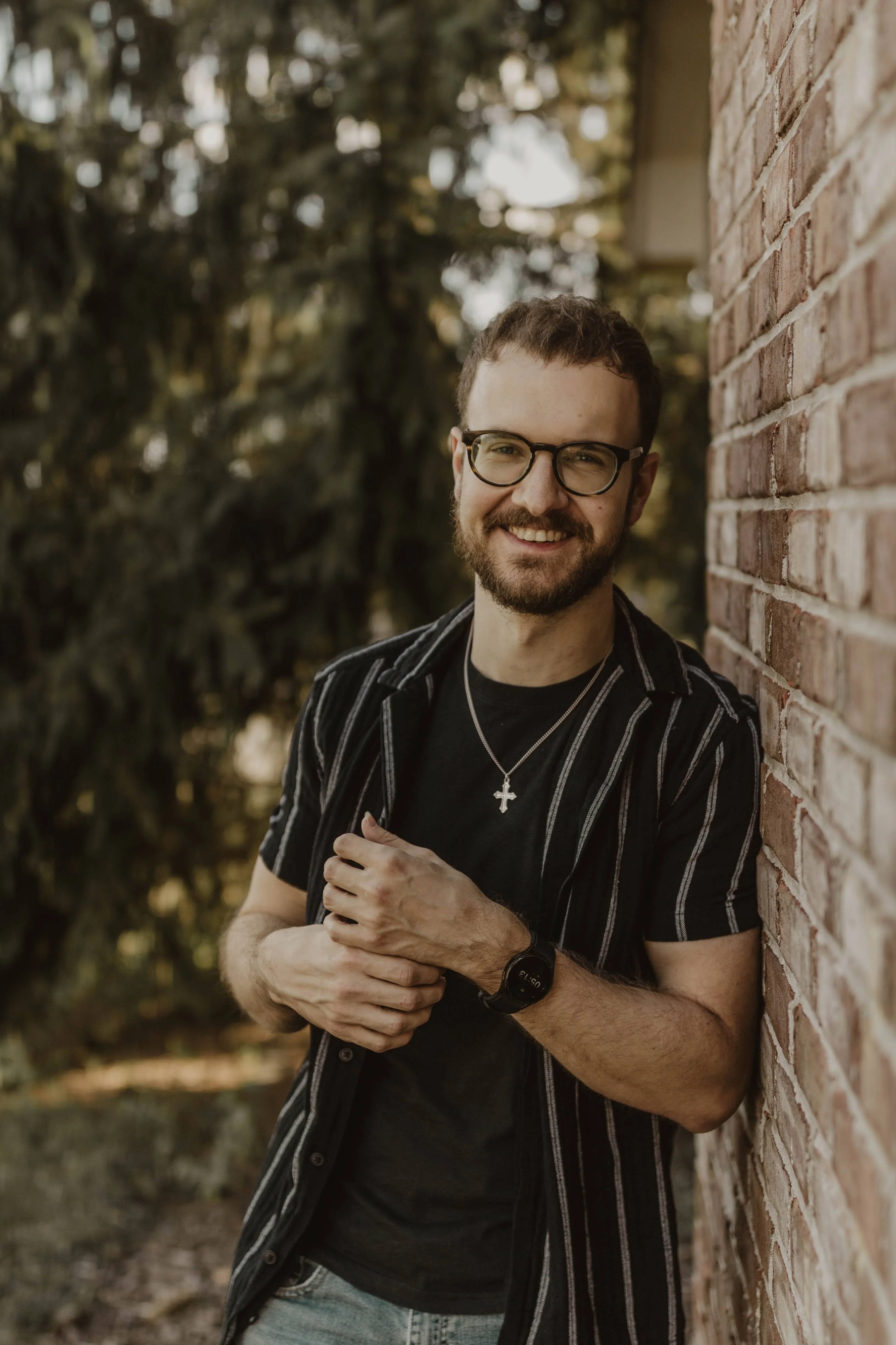 Jeremy Shull smiling beside a brick wall outdoors.